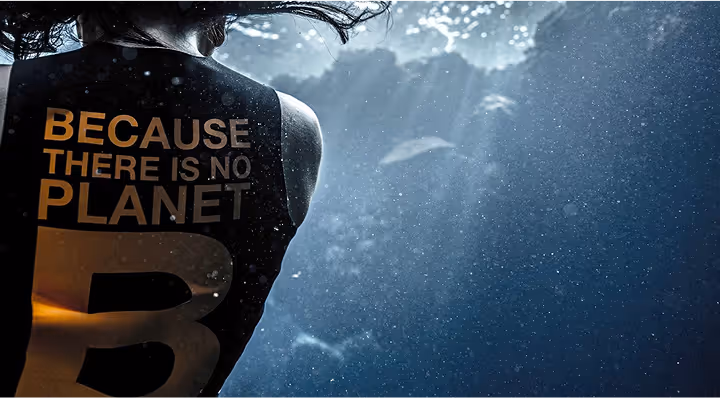 Imagen de una persona de espaldas bajo el agua con una camiseta que pone en inglés 'Porque no hay planeta B'.